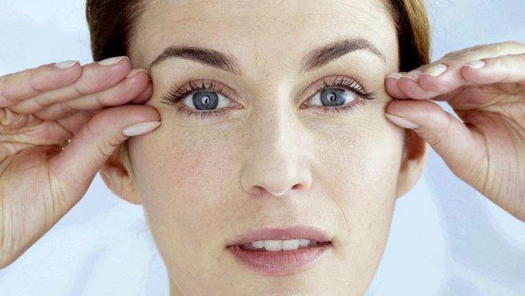 Женщина держит пальцы возле глаз